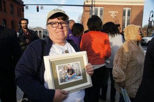 Leslie Boyd holds a picture of Mike, lost at 31 from cancer and denied health care due to a pre-existing condition.